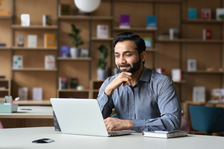 Indian man smiling at laptop